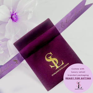 a close up of a purple ribbon with a flower in the background